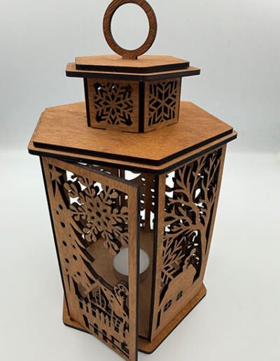 Wooden Christmas lantern with detailed winter village and snowflake cutout design, handmade decorative candle lantern.