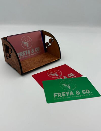 Custom wooden business card holder with curved sides and branded cards displayed in front.