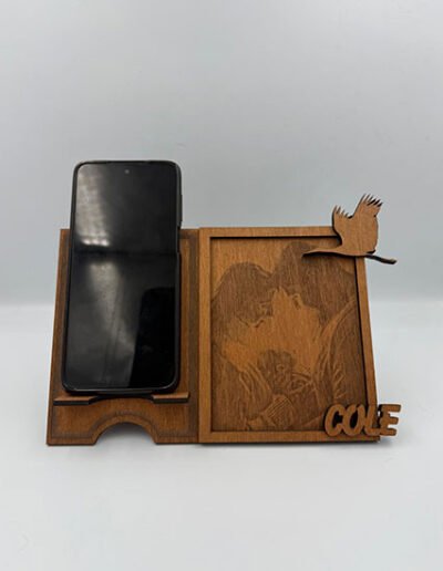 Personalized wooden phone stand with engraved photo panel, bird detail, and custom name.