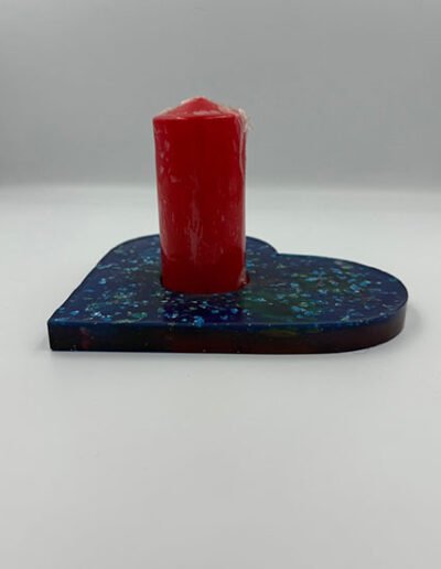 Heart-shaped resin candle holder with a red pillar candle.